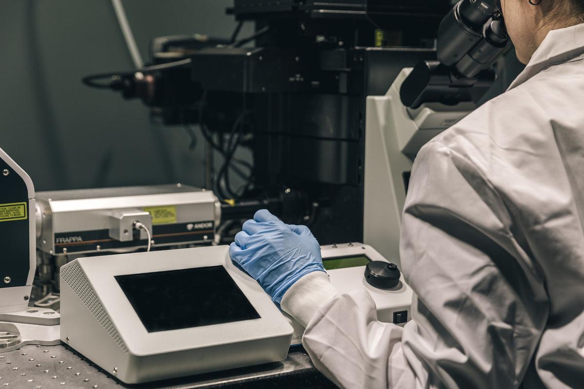Service engineer aligning optics on a microscope at a customer bench